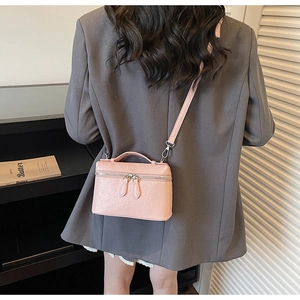 Pink ostrich pattern square bag with silver double zippers shown from a back-view model pose