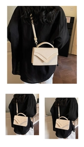 Detail of cream white rectangular crossbody bag with V-shaped flap and gold hardware details