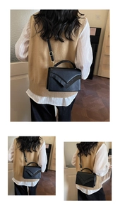 Detail of black pebbled leather handbag with V-shaped flap and gold hardware accents