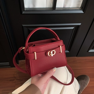 Detailed macro view of red litchi grain leather texture and gold metal twist lock