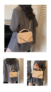 Detail view of beige crossbody bag featuring unique V-shaped pleated design and adjustable strap