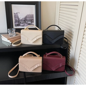 Detail of minimalist leather crossbody bags in four colors with V-shaped pleats and tassels