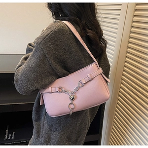 Pink lychee grain leather baguette bag detail with heart pendant and silver chain strap