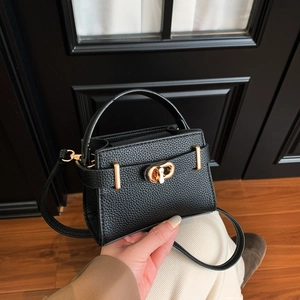 Detail of black lychee grain leather mini bag with gold twist lock held by a person