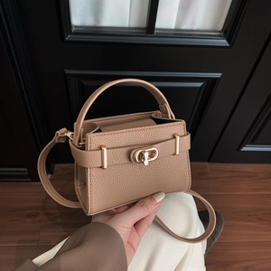 Close-up of pebble grain leather texture and gold twist-lock on mini handbag