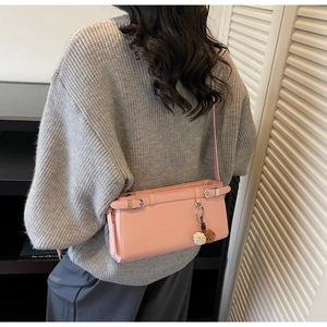 Pink rectangular PU leather crossbody bag featuring metal buckles and pompom charm