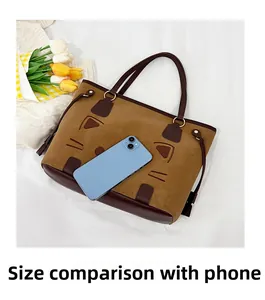 Detail of khaki tote bag with cat face embroidery and phone for size comparison