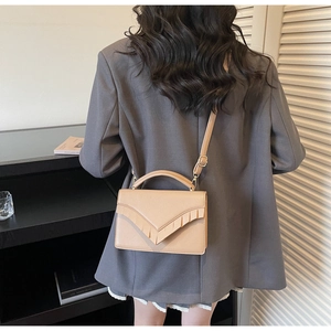 Detail of beige faux leather handbag with tassel decor and adjustable shoulder strap