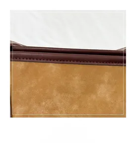 Close-up of brown leather stitching and matte texture on a stylish shoulder tote bag