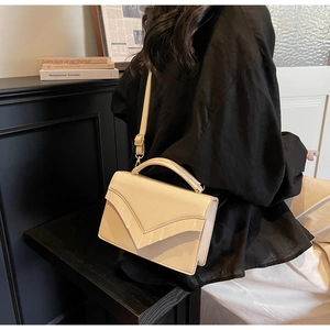 Detail of cream white pebbled leather handbag featuring a unique V-shaped flap design