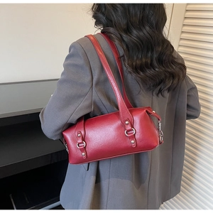 Vista posteriore di una borsa Boston in pelle rossa indossata come borsa a spalla con un completo
