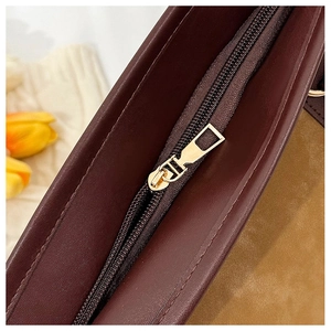 Vue macro d'une fermeture éclair dorée et du cuir texturé d'un sac cabas marron