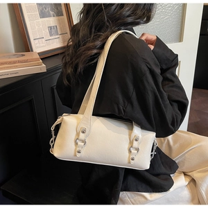 Dettaglio della borsa bowling in pelle crema con borchie argentate sulla tracolla alla moda