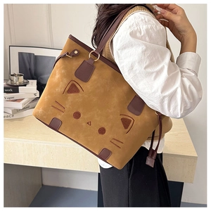 Détail d'un grand sac cabas en daim avec une broderie de visage de chat sur le devant