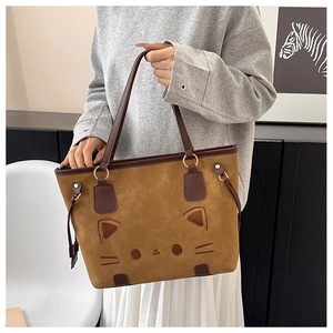 Detail of brown cat patterned tote bag showing embroidery and metallic handle rings