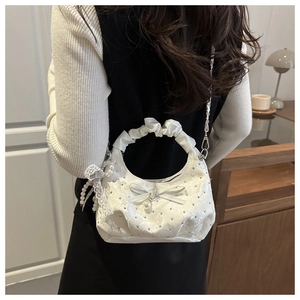 Detail of white lace handbag with satin bow and pearl pendant on a silver chain