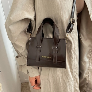 Fashionable dark brown glossy leather handbag for women with metallic shoulder strap