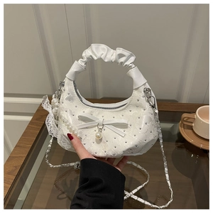 Close-up of white lace floral handbag with pearl charms and rhinestone details