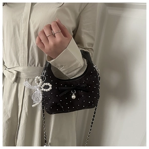 Dettaglio borsa hobo nera con borchie, fiocco di pizzo, perle e tracolla a catena