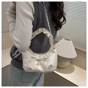Dettaglio della borsa in pizzo bianco con fiocco in pelle, perla e catena d'argento