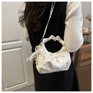 Detail of white lace handbag with delicate bow, pearl pendant and sparkling rhinestones
