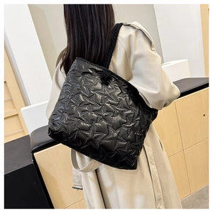 Detail view of large black quilted tote bag with star pattern and soft rope handles