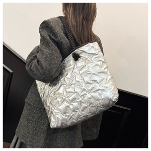 Detail of silver quilted star pattern tote bag with thick black braided shoulder strap