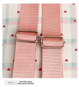 Detail view of pink strap with silver metal adjustment buckles on plaid fabric