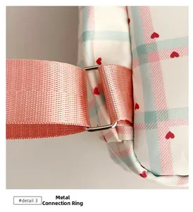 Detail view of pink plaid fabric with red hearts and silver metal D-ring attachment