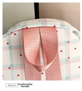 Detail of the comfortable pink woven handle on a plaid backpack with red heart patterns