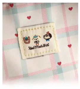 Macro detail of plaid fabric with heart prints and handmade embroidery label for school bag