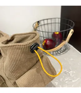 Dettaglio della borsa tote in velluto a coste kaki con coulisse arancione e fibbia nera