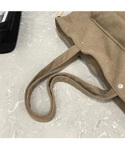 Dettaglio della borsa tote in velluto a coste con bottone a pressione e doppi manici