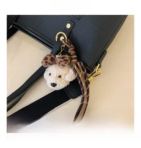 Détail du charm chiot en peluche et ruban rayé sur sac cabas en cuir grainé noir