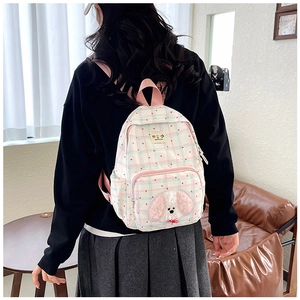 Close-up of pink checkered backpack featuring a plush puppy patch and heart patterns