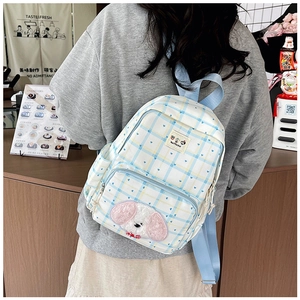 Detail of blue and white checkered mini backpack with cute dog embroidery and heart patterns