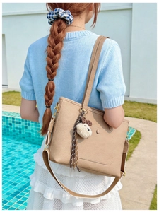 Mannequin portant un sac cabas en cuir kaki avec charme en peluche et ruban rayé
