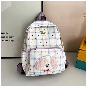 Close-up of blue and yellow plaid backpack with plush puppy patch and purple side pocket