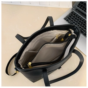 Detailed interior of large black leather tote bag with compartments and beige lining