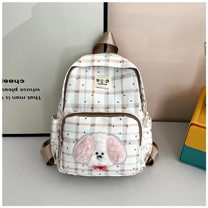 Detail of checkered backpack featuring a plush puppy patch and red heart accents