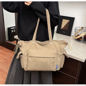 Dettaglio borsa tote in velluto a coste kaki con grande tasca frontale e lacci laterali