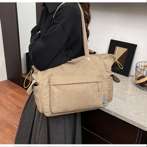 Vista laterale dettagliata della borsa tote in velluto a coste kaki con tasche laterali