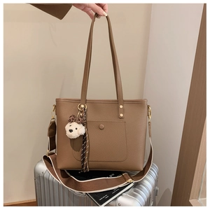 Detail of brown litchi pattern leather tote with striped strap and plush bear charm