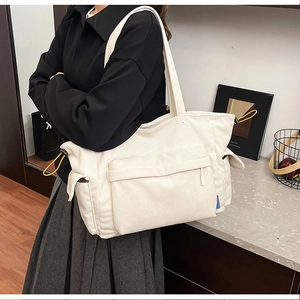 Dettaglio della borsa tote in velluto a coste bianco con tasca zip e lacci gialli