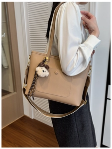 Close-up of khaki tote bag with litchi grain texture and a cute plush bear charm