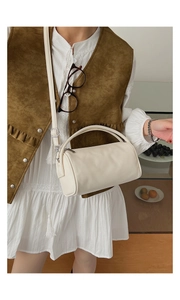 Detailaufnahme der weißen Zylindertasche mit Lychee-Muster und elegantem Outfit