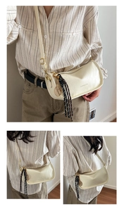 Detail of off-white curved shoulder bag with vintage texture and gold tennis charm