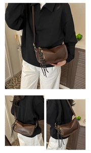 Detail view of a dark brown crossbody pillow bag with gold hardware and woven pendant
