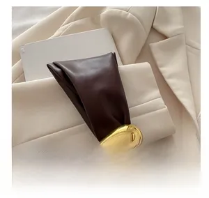 Close-up of brown pleated bucket bag with a streamlined gold metal buckle detail