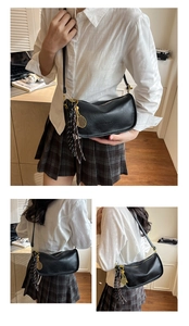 Detail of black crescent moon bag featuring a gold tennis racket charm and plaid bow